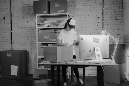 Woman writing down on a Carton Box while looking at a Clipboard